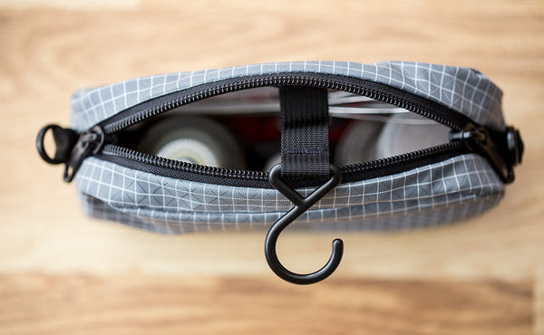 An assortment of items in a 3D Organizer Cube with the zipper open and hanger hook out.